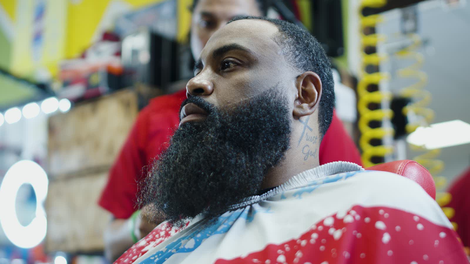 Barber shaping a client's beard in the chair